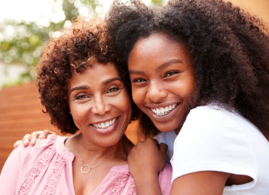 Mother and daughter smiling towards a camera