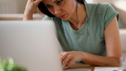 Woman starring at a laptop with her hand on her head