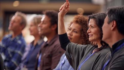 Women in a group of people raising her hand.